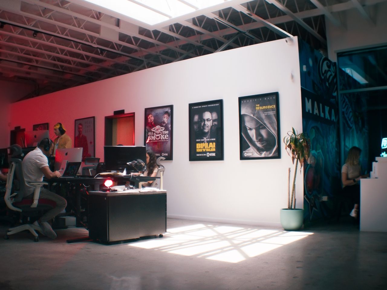 Creative office space at Malka. Work stations and people to the left, reception desk to the right.